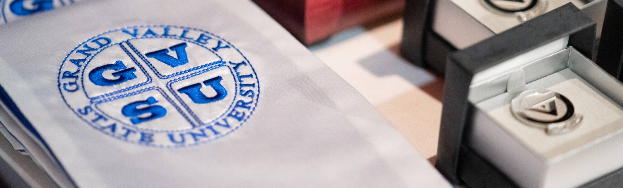 Close up of GVSU-branded cuff links and decorative sash with GVSU seal.